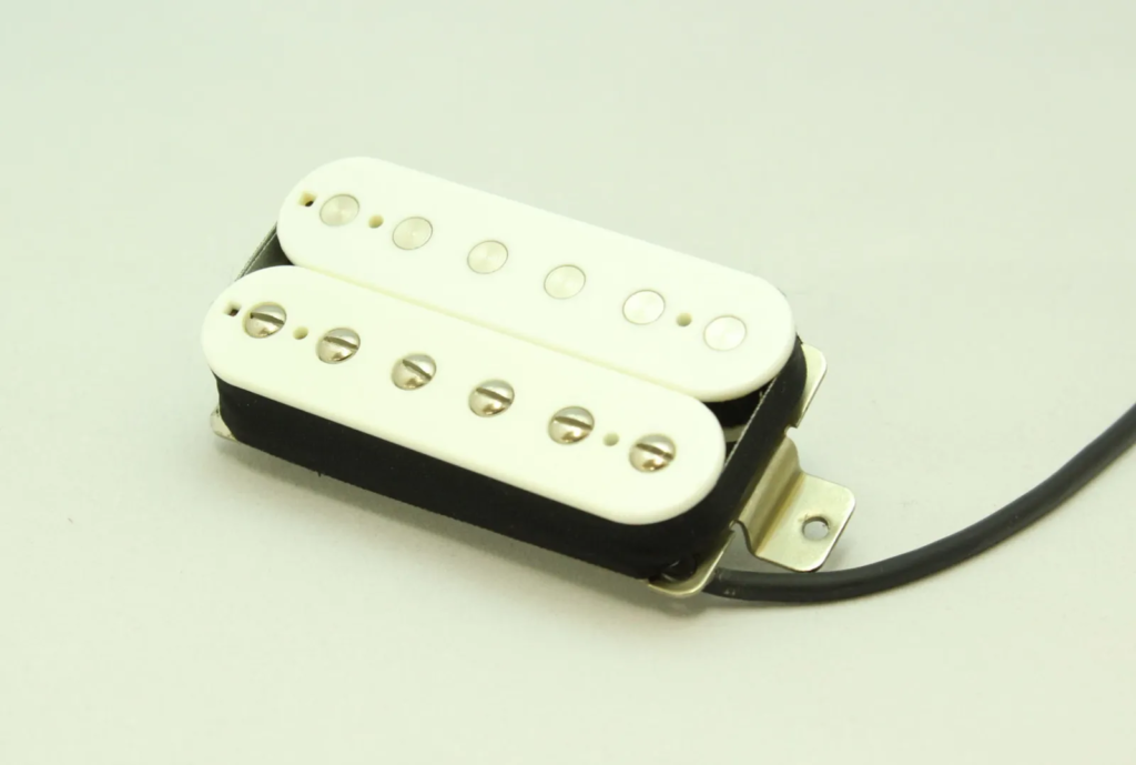 Saytone humbucker guitar pickup with white bobbins, exposed pole pieces, black baseplate, and attached lead wire on a light background.
