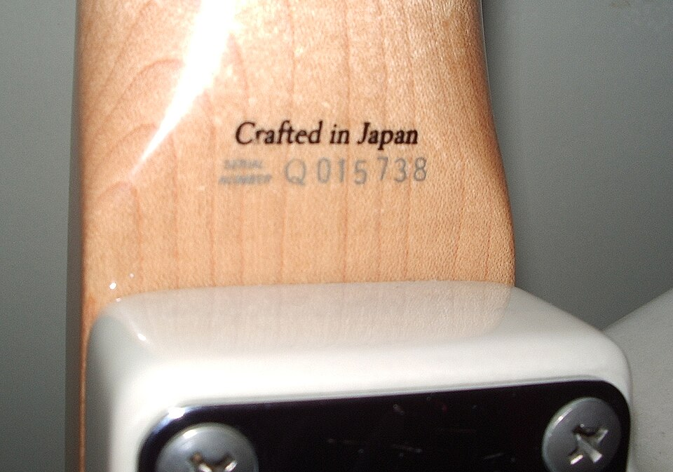 Close-up of a guitar neck heel stamped “Crafted in Japan” with serial number, a marking commonly seen on instruments manufactured by Dyna Gakki in Japan.