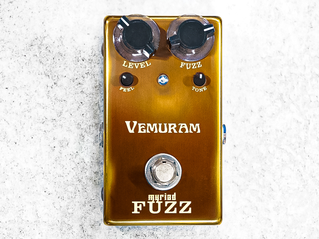 Vemuram Myriad Fuzz guitar pedal in a gold enclosure with level, fuzz, tone, and feel controls and central footswitch, shown from above.