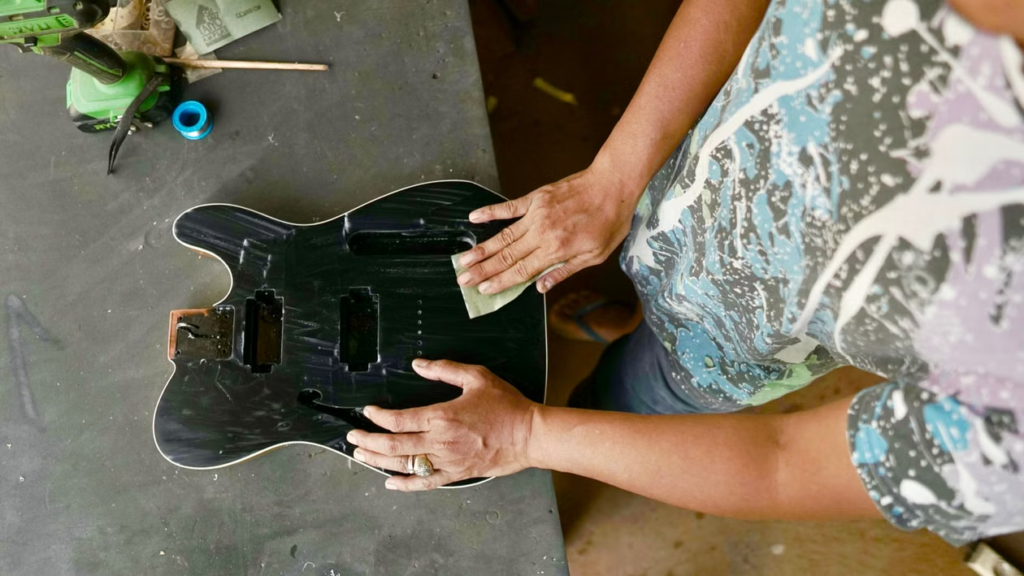 A person cleaning the body of an electric guitar
