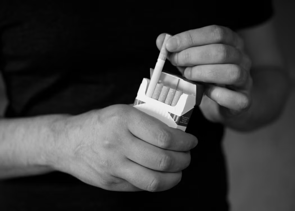 A person taking a cigarette from a pack
